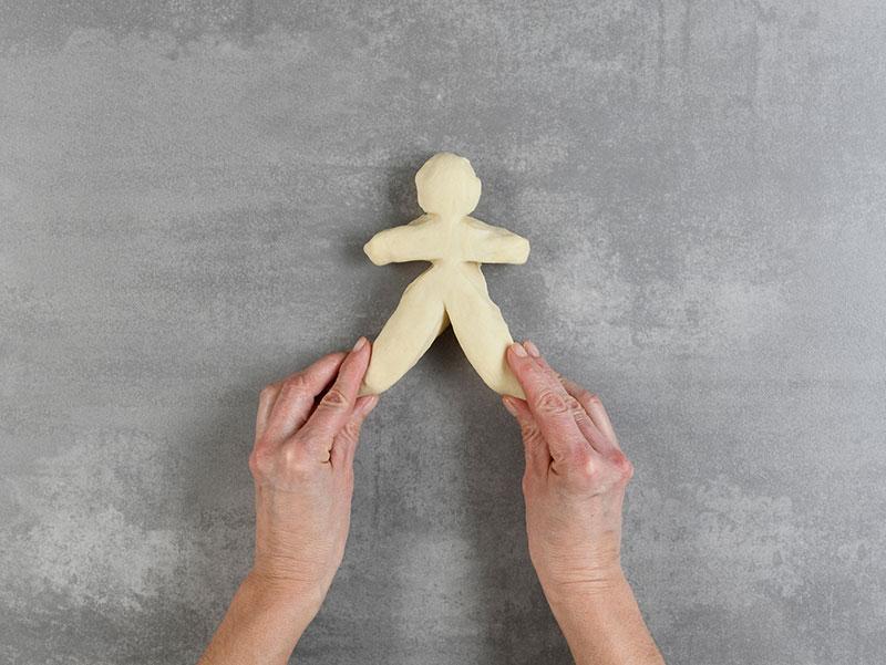 Hände formen aus Teig eine Figur.