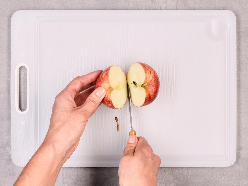 Ganze Apfel wird mit Messer in zwei Hälften geschnitten.