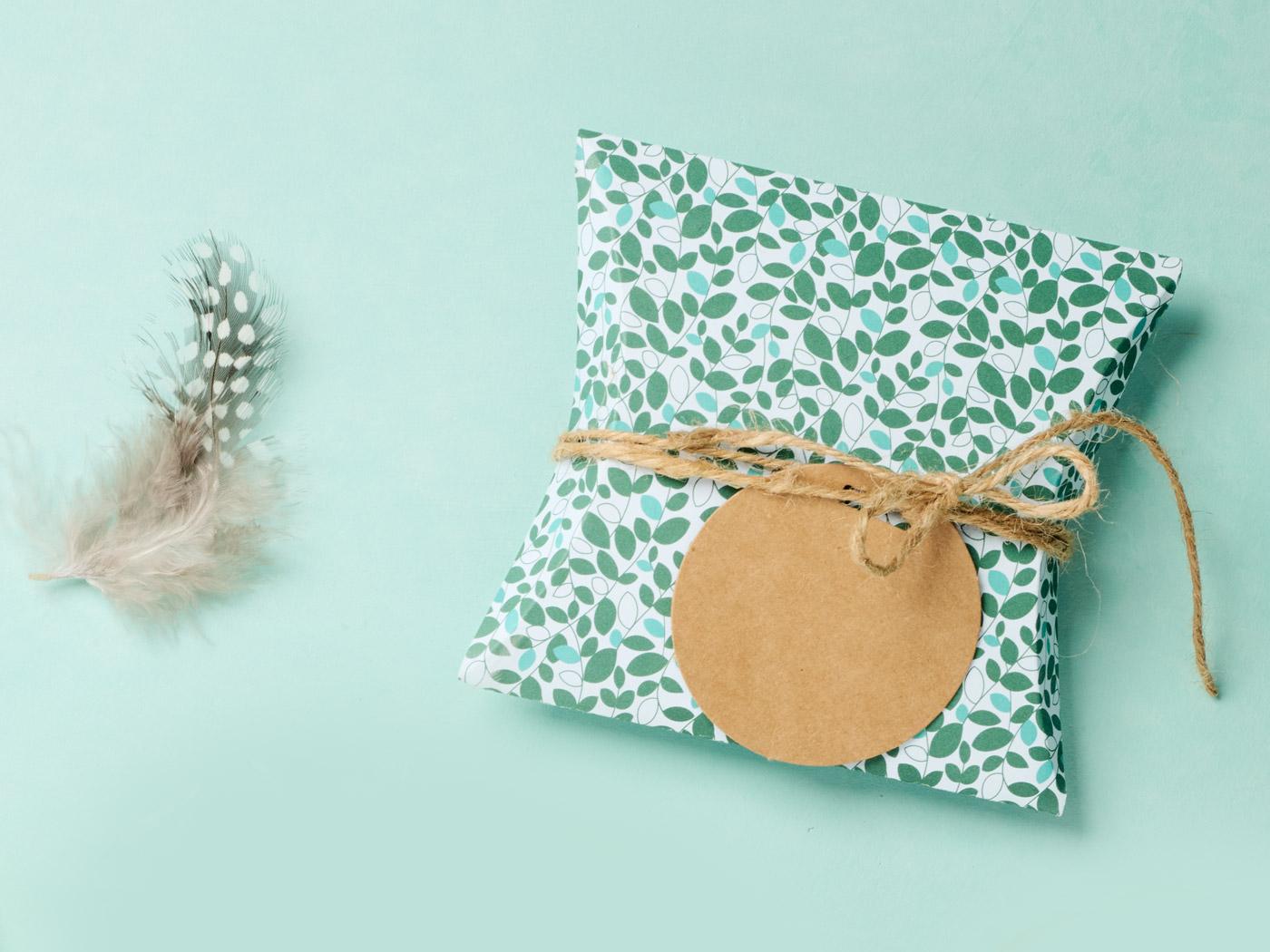 Pillowbox mit grünem Blättermuster, umwickelt mit Schnur und Anhänger.