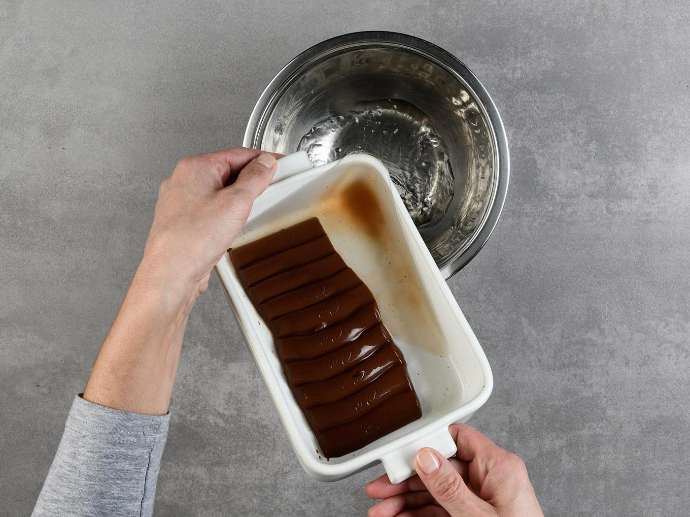 Hand kippt weisse Form mit heissem Wasser in Metallschüssel.