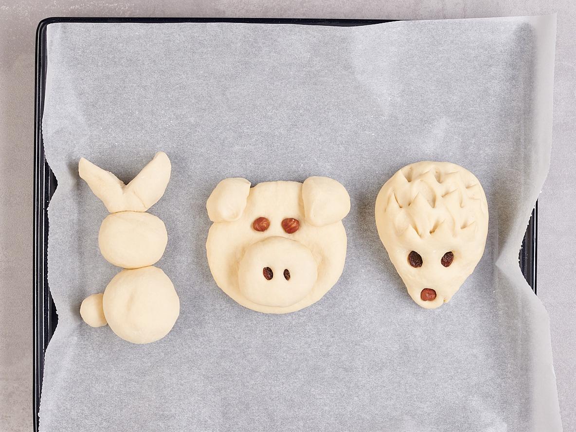 Drei Teigfiguren – Hase, Schwein und Igel – auf Backpapier.