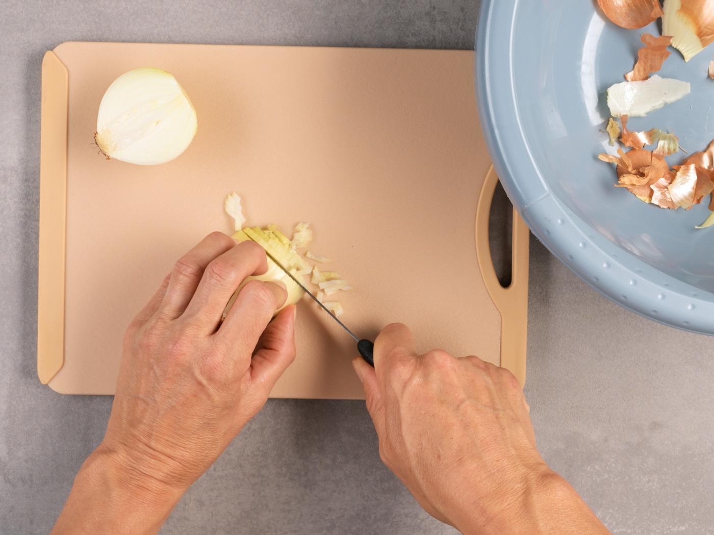 Zwiebelhälfte wird quer in kleine Stücke geschnitten.