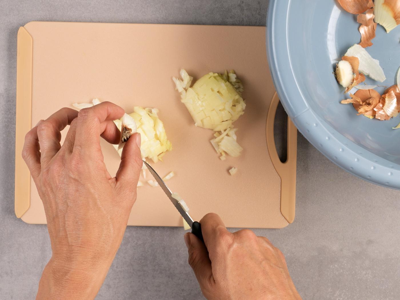 Messer schneidet das Ende der Zwiebelhälfte ab.