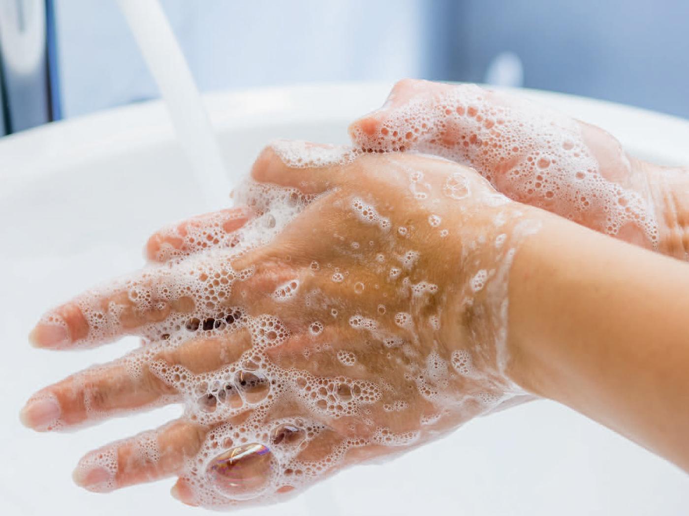 Hände mit viel Seifenschaum werden unter fliessendem Wasser gewaschen.